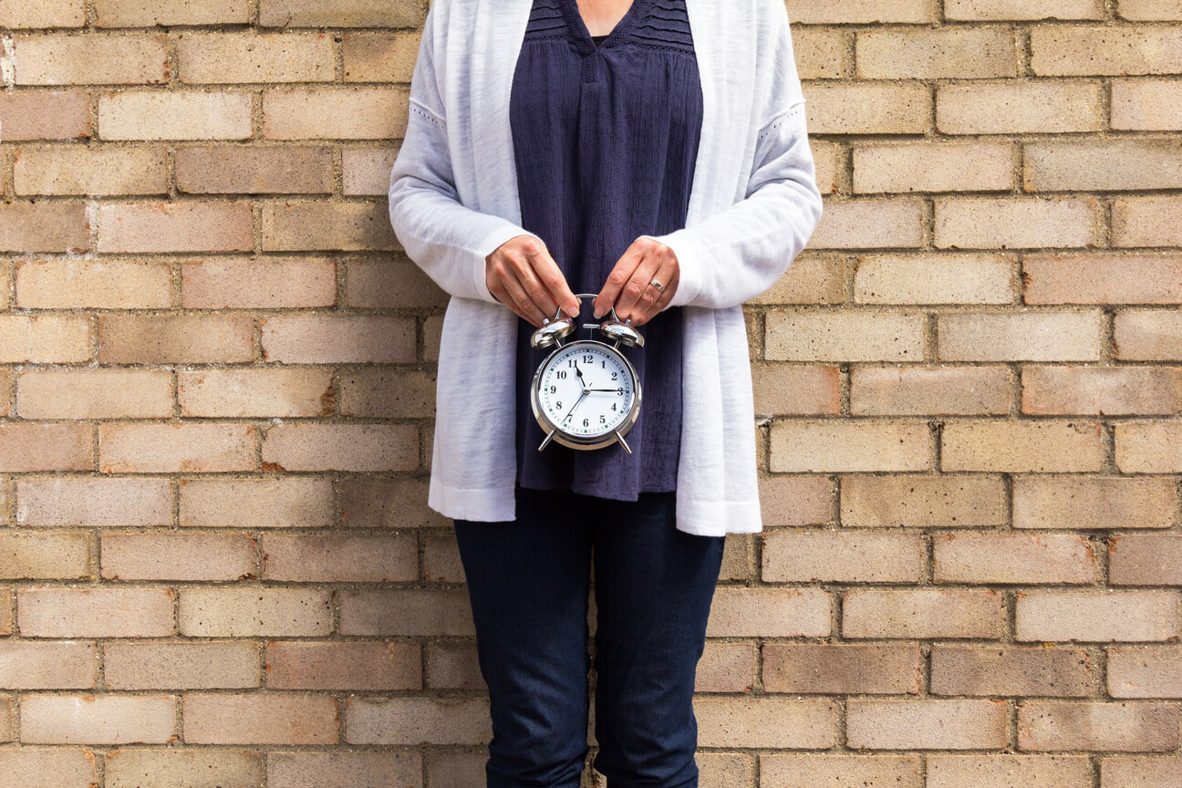Biological Clock Concept Woman holding a clock in front of her