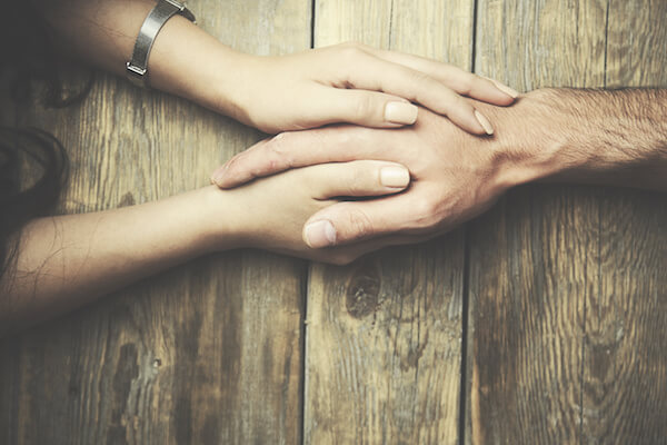 man and a woman holding hands at a wooden table