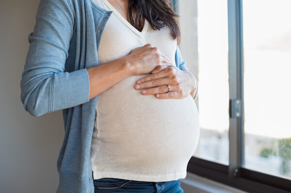 Close up of pregnant woman touching her belly. Lovely young woman expecting a baby. Pregnant woman hugging her tummy.