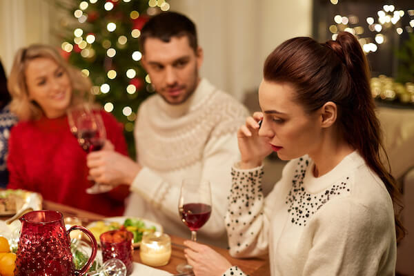 holidays, communication and celebration concept - young woman calling on smartphone and having christmas dinner with friends at home