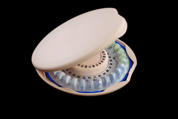 Birth Control Pills in a pink circular dispenser on a white background