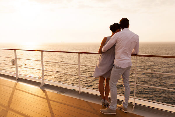 back view of young couple hugging at sunset on cruise ship