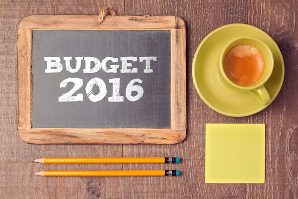 Business concept of budget for 2016 new year. Chalkboard with coffee cup on wooden desk.