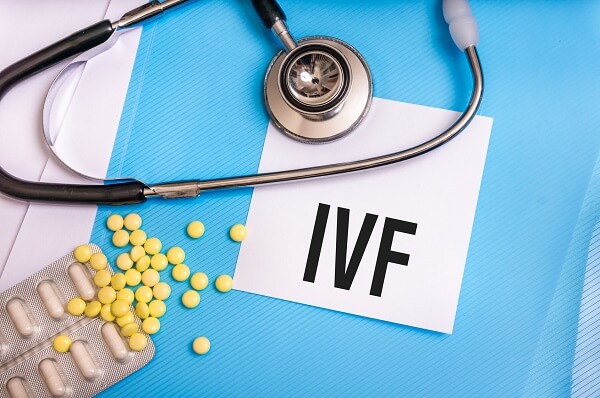 IVF word written on medical blue folder with patient files, pills and stethoscope on background