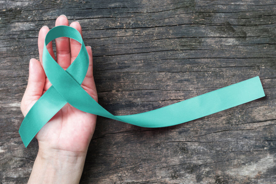 Teal ribbon awareness on woman's hand for Ovarian Cancer, Polycystic Ovary Syndrome (PCOS) disease, Post Traumatic Stress Disorder (PTSD), Tourette's Syndrome, Obsessive Compulsive Disorder (OCD)