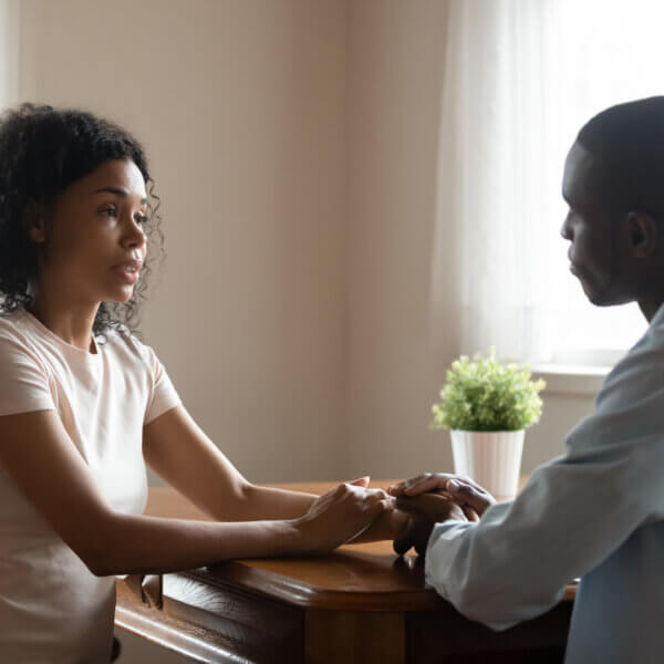 Couple Infertility Symptoms. Couple at table holding hands discussing together.