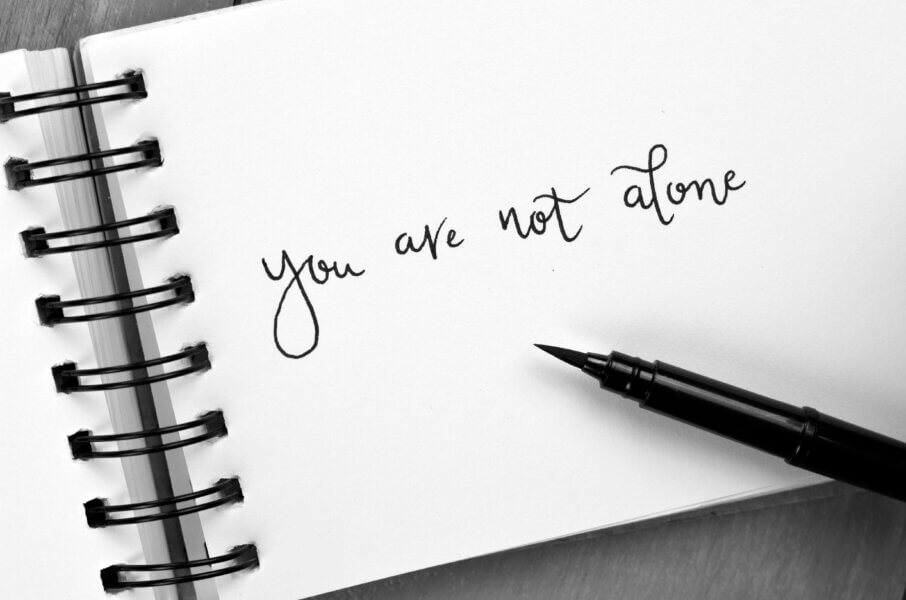 You are not alone written in book with black pen
