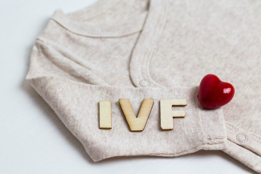 Baby clothes with test-tube and heart. Concept - IVF, in vitro fertilization. Waiting for baby, pregnant.