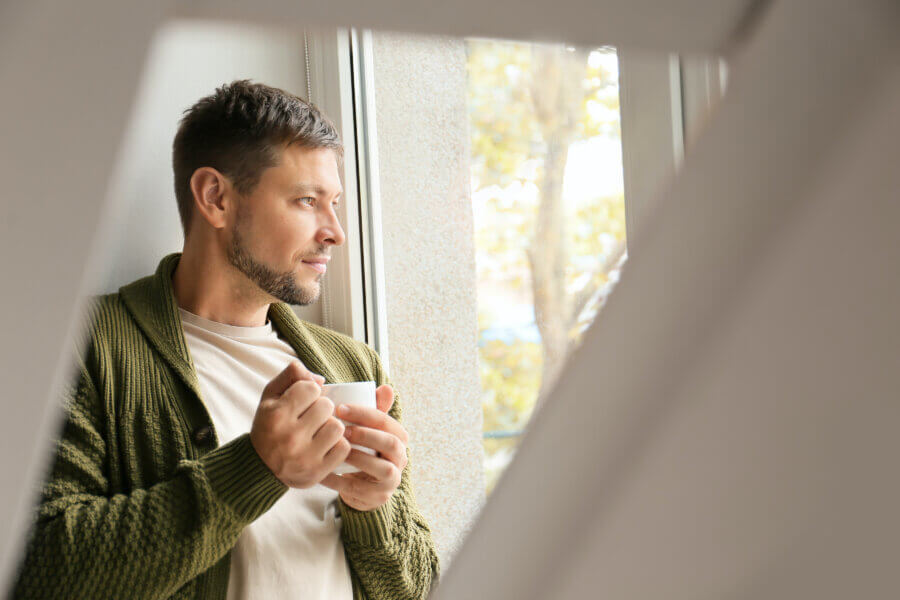 male infertility Man with cup of tea relaxing near window at home