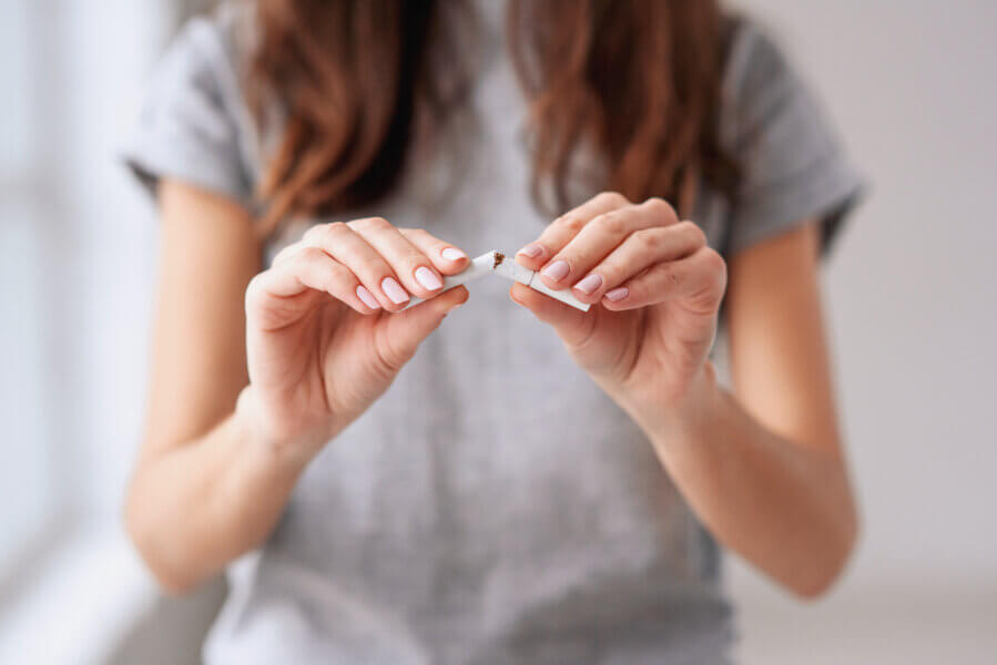 tobacco use Stop smoking cigarettes concept. Portrait of beautiful smiling girl holding broken cigarette in hands. Happy female quitting smoking cigarettes. Quit bad habit, health care concept. No smoking.
